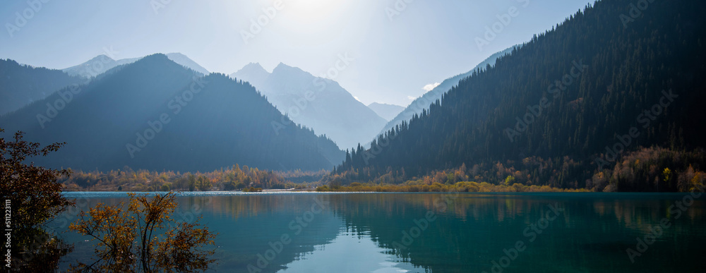 Selective focus. Serenity lake in the mountains. Foggy autumn morning with mountains and reflection.