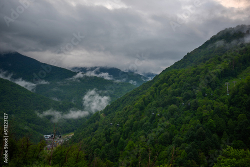 Selective focus. Spring morning at mountains and clouds. Atmospheric landscape with trees and low clouds on cloudy sky. Awesome mountain scenery.