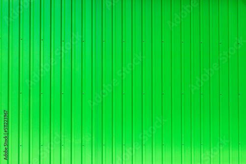 Green wall is made of metal. Texture of building. Bright surface.