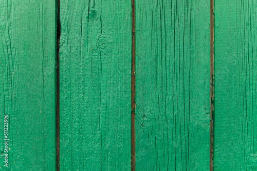 A background of green peeling paint on an old wooden wall. Uneven texture of the boards.