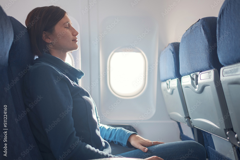 Fear of flying woman in plane sick with stress headache and motion sickness or airsickness. travel with airplane with aerophobia is afraid to fly, sitting on seat of plane. - obrazy, fototapety, plakaty 