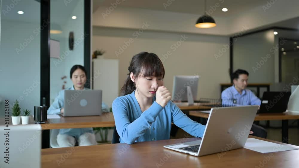 Young employee Asian woman is tired at her work place with laptop computer and falls asleep Young employee Asian woman is tired at her work place with laptop computer and falls asleep