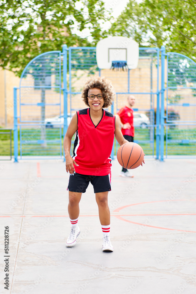 Fototapeta premium girl with afro hairstyle with a ball on a basketball court
