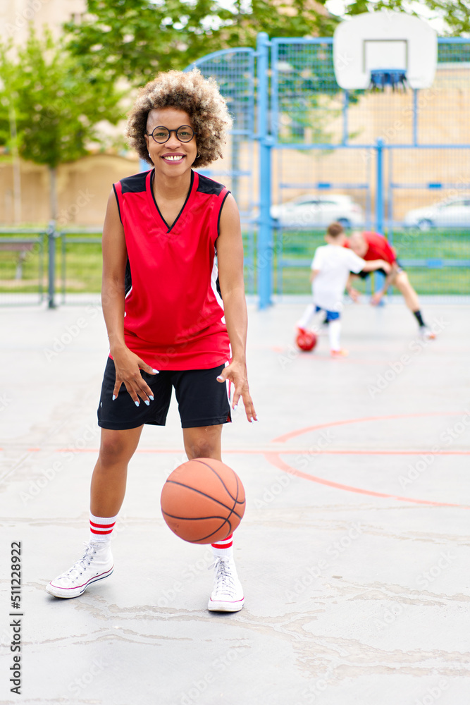 Obraz premium girl with afro hairstyle with a ball on a basketball court