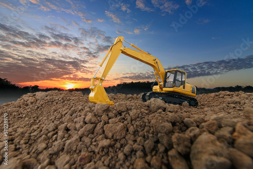 Excavators are digging soil with in the construction site on sky with sunset background