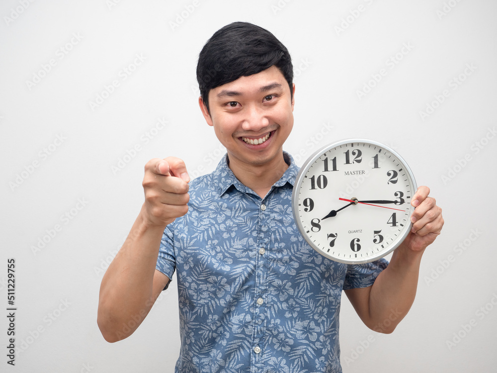 Cheerful man holding clock smiling point finger at you isolated Cheerful man holding clock smiling point finger at you isolated