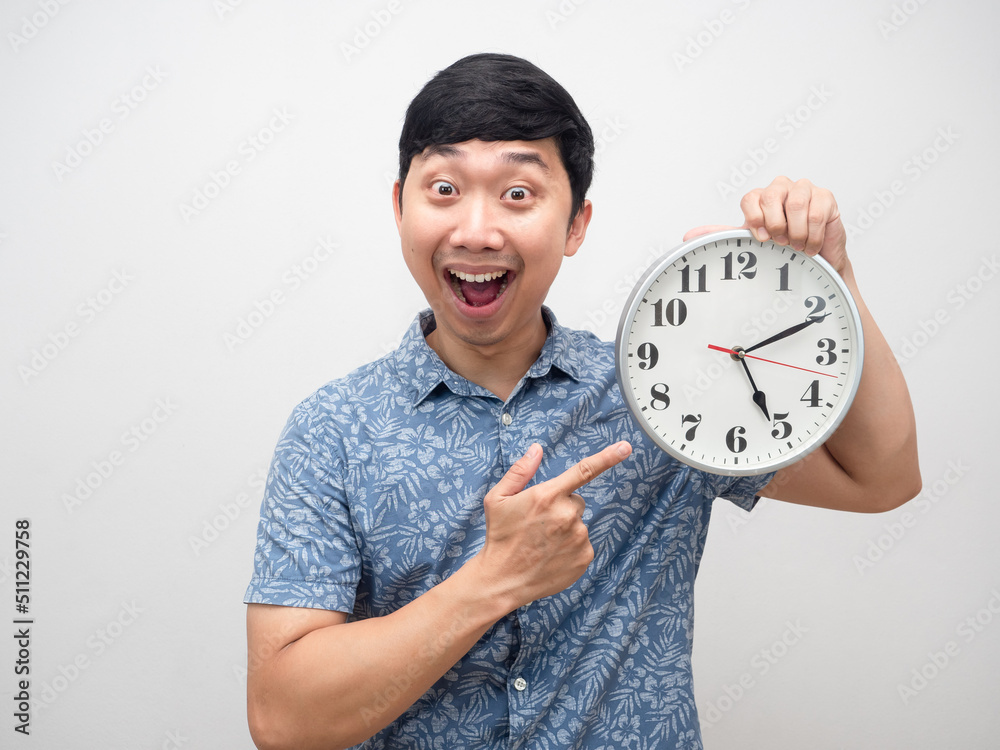 Positive man happy smile about finish working point finger at analog clock pm Positive man happy smile about finish working point finger at analog clock pm