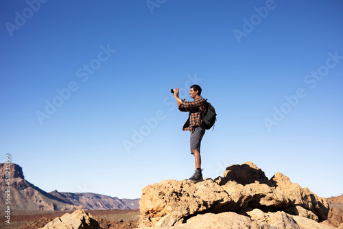 Young man taking pictures on a road trip. Man making memories on the mountain.