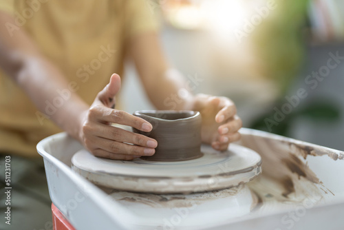 Craftsman hands making pottery bowl. Woman working on potter wheel. Family business shop sculpts pot from clay.