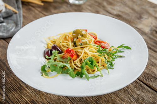 Portion of italian spaghetti pasta with olives and herbs