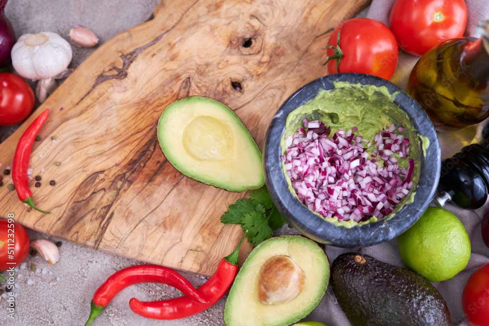 making guacamole - crushed avocado in marble mortar and ingredients making guacamole - crushed avocado in marble mortar and ingredients