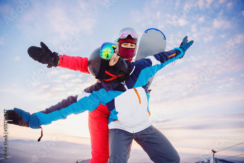 Happy couple man and woman snowboarders background sunset ski resort. Concept friends travel love winter