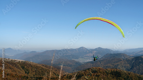 Paragliders flying in the blue sky with mountain in background.