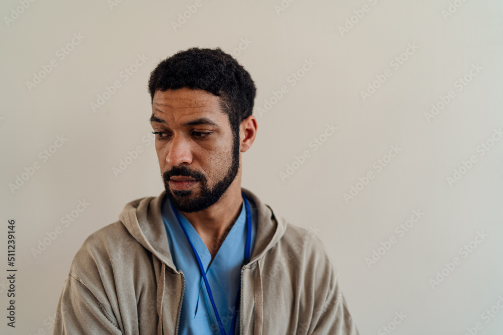 Fototapeta premium Depressed young male doctor or caregiver over beige background.