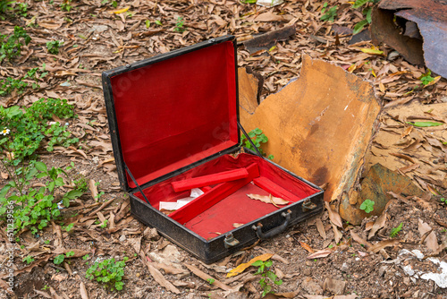 An abandoned red and black empty suitcase in the wild