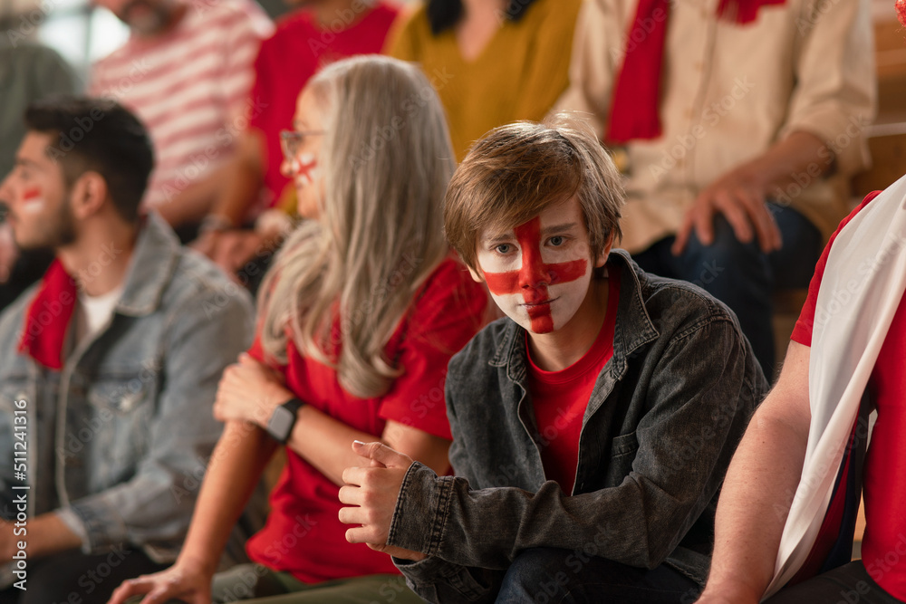 Fototapeta premium Excited football fans supporting English national team in live soccer match at stadium.
