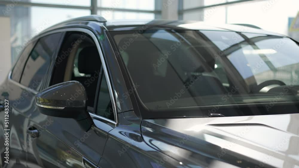 Closeup view of new black transport is standing in modern dealership office spbas. 4k Motion shot of window and shiny surface of luxury car stands in bright sales room and is presented for rent or Closeup view of new black transport is standing in modern dealership office spbas. 4k Motion shot of window and shiny surface of luxury car stands in bright sales room and is presented for rent or