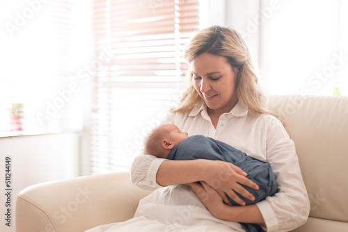 Young mother holding her newborn son at home.