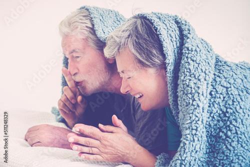 фотографія Mature couple having fun together in the bed under the cover laughing and joking as young