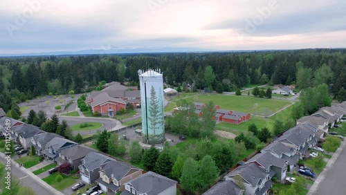 Orbiting aerial shot around a suburban water tower with an elementary school in the background. photo