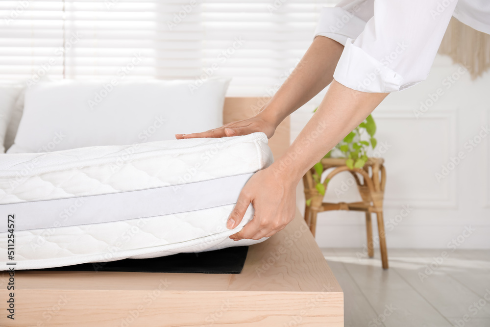 Woman putting soft white mattress on bed indoors, closeup Woman putting soft white mattress on bed indoors, closeup
