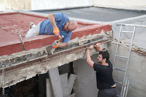 Photography Two masons removing old metal beams in a construction house.