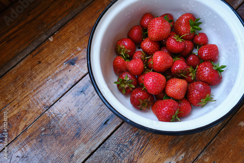 Bowl of fresh organic strawberries on a wooden background. Ripe farm fruits. Seasonal berries. Healthy food, vitamins. Bioproducts selected by hand