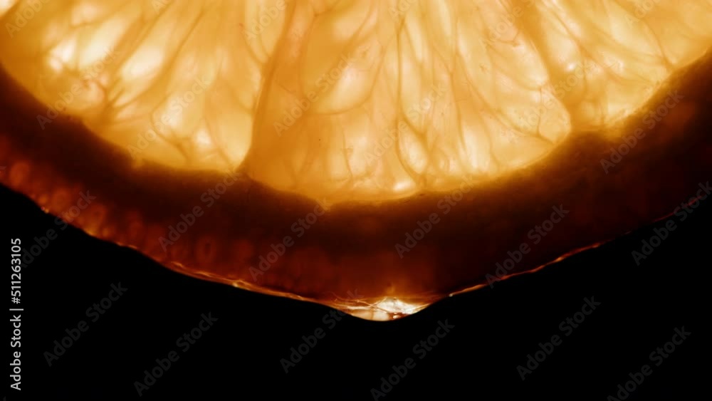 Juicy orange slice on black background. Citrus fruit close-up texture, healthy sweet food. Summer refreshment concept.