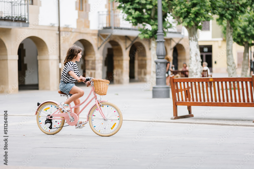 Fototapeta premium elementary caucasian girl rides in the square on a bicycle