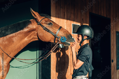 female professional rider bonding with her horse - thoroughbred connecting and smiling to her human partner © Carlo