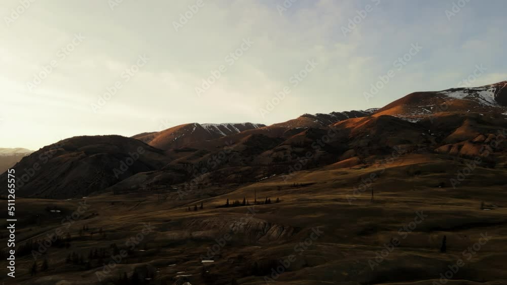 Mountains of unusual color at sunset. Mountain tops with snow. Brown earth in the shade. Mountains of unusual color at sunset. Mountain tops with snow. Brown earth in the shade.