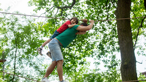 Cute child and father, boy and dad, climbing in a rope playground structure