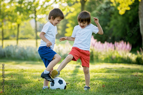 Two cute little kids, playing football together, summertime. Children playing soccer © Tomsickova