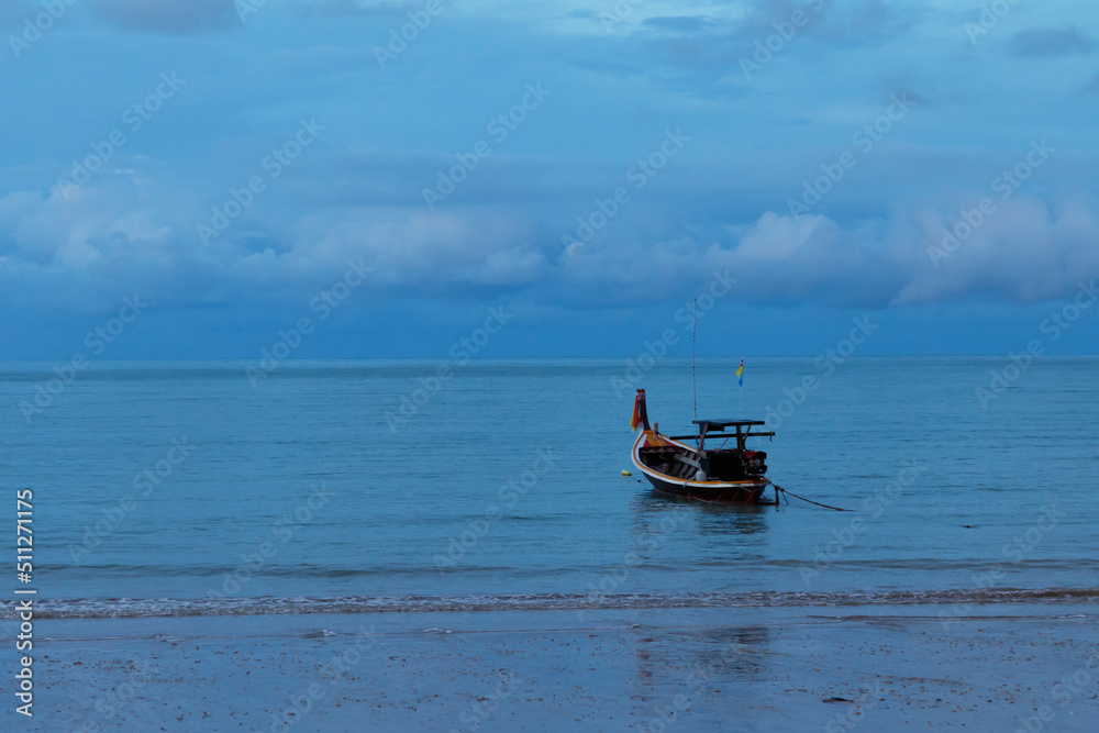 Fototapeta premium Fishing boat floating in calm sea near sandy beach.