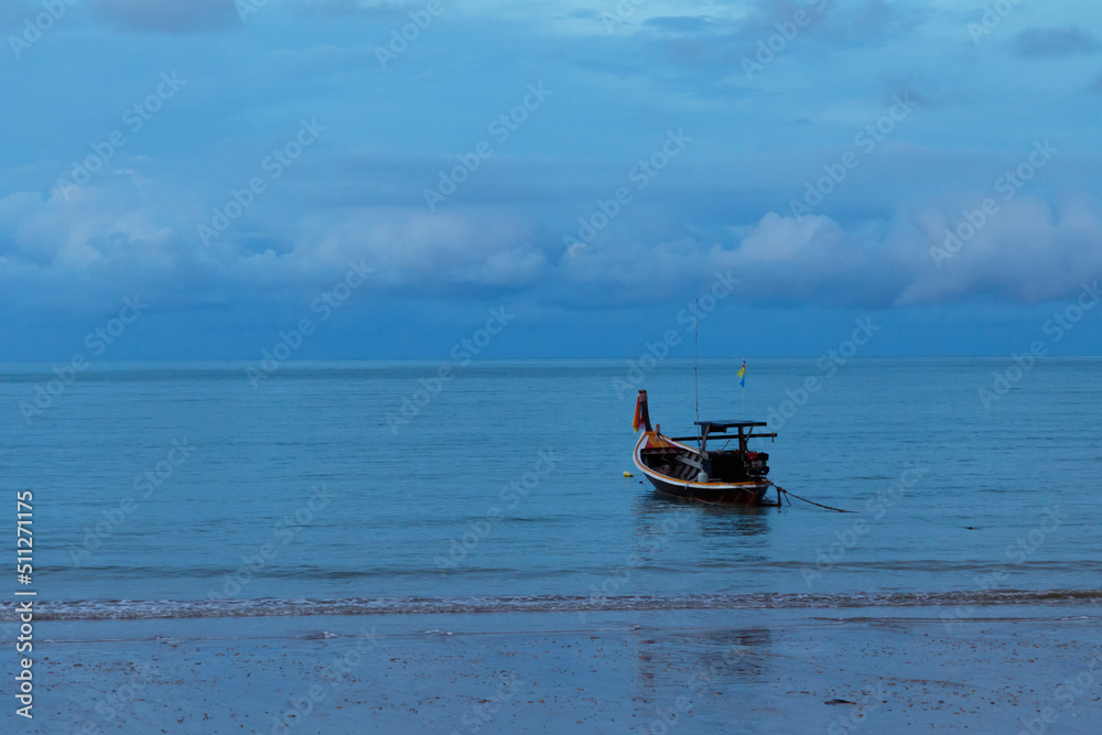 Fishing boat floating in calm sea near sandy beach.