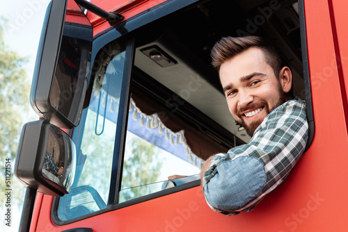 Happy male truck driver inside his red cargo truck