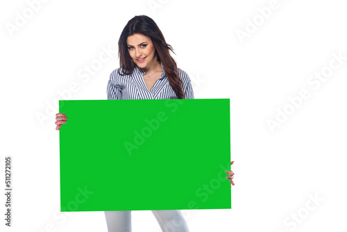 Beautiful brunnet сaucasian young girl in white pants and striped shirt holding big advertising plate isolated on white background photo