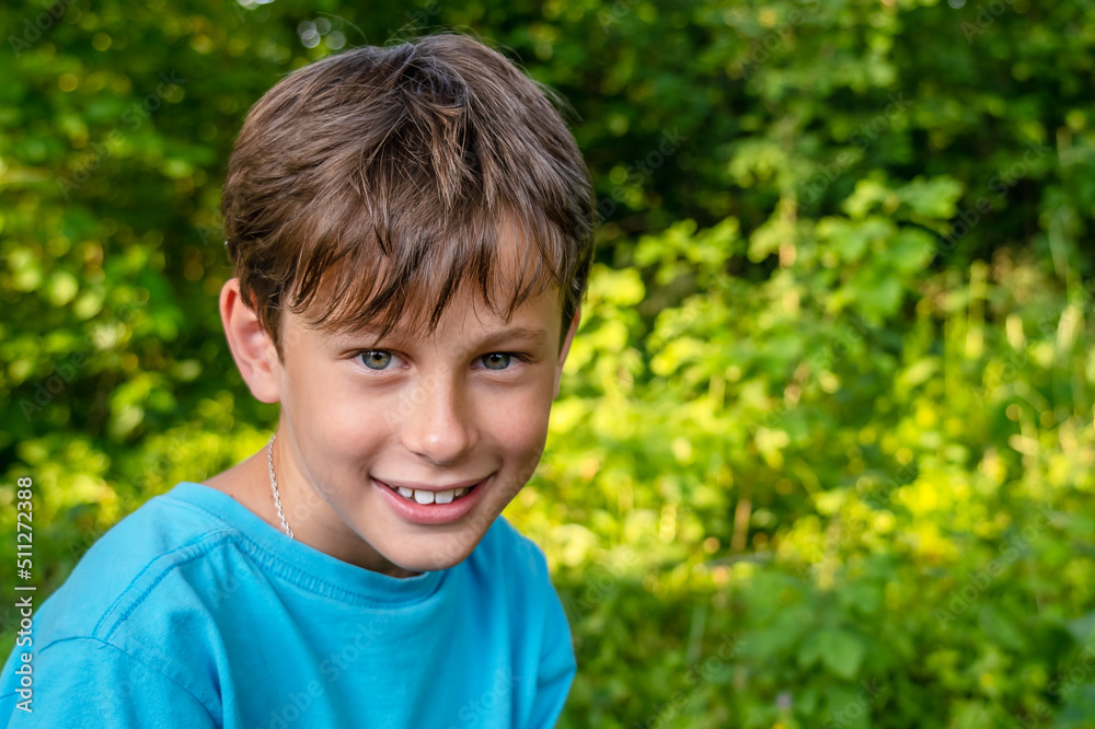 Smiling boy. Portrait of a smiling 9-year-old boy in a blue t-shirt in the garden against the background of trees Smiling boy. Portrait of a smiling 9-year-old boy in a blue t-shirt in the garden against the background of trees