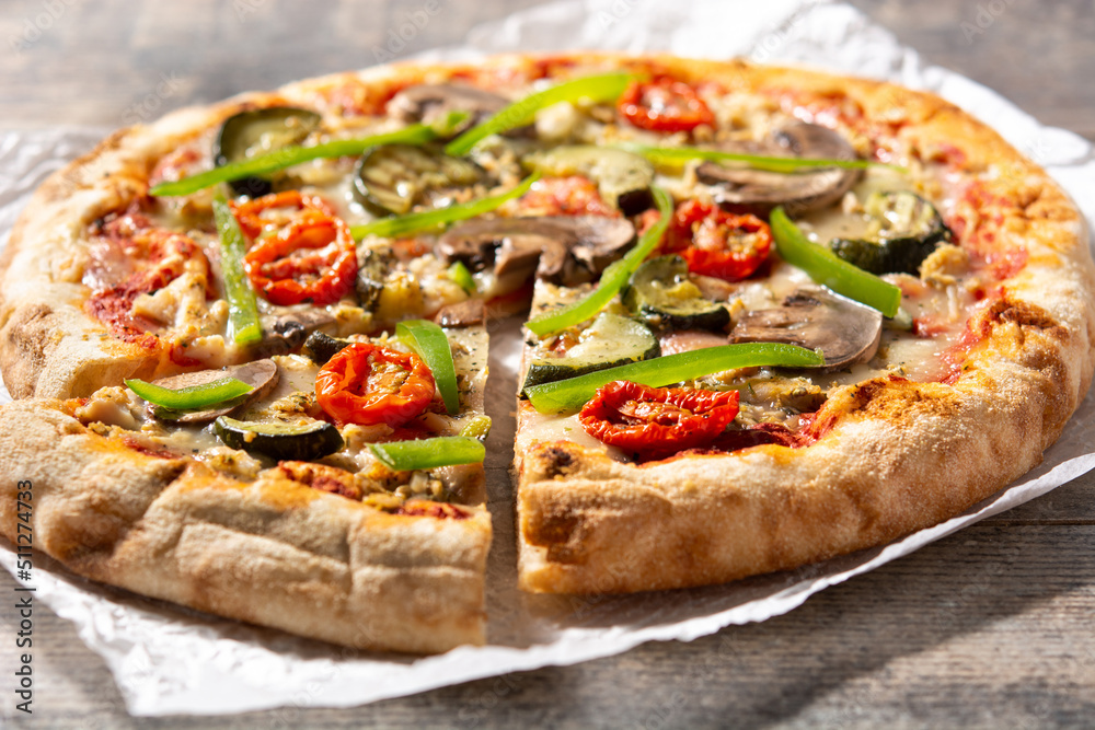 Vegetarian pizza with zucchini, tomato, peppers and mushrooms on wooden table	