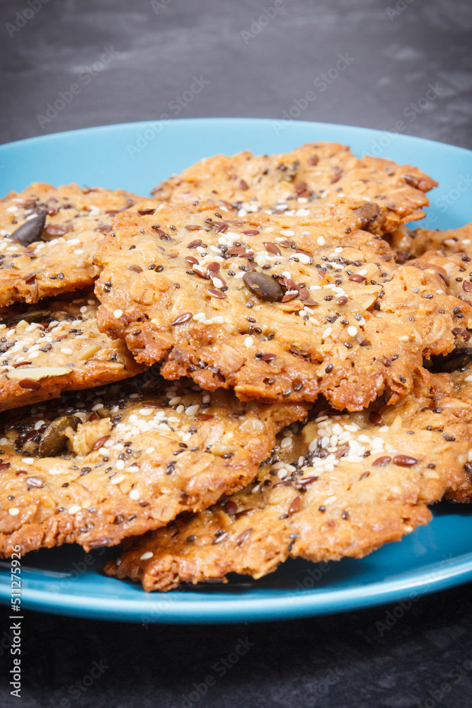 Fresh baked oatmeal cookies with honey and healthy seeds on blue glass plate. Delicious crunchy dessert Fresh baked oatmeal cookies with honey and healthy seeds on blue glass plate. Delicious crunchy dessert