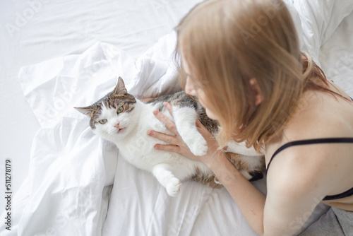 Female hugging cat in hands on the bed at home. Stay home stay safe. Love, care, adoption