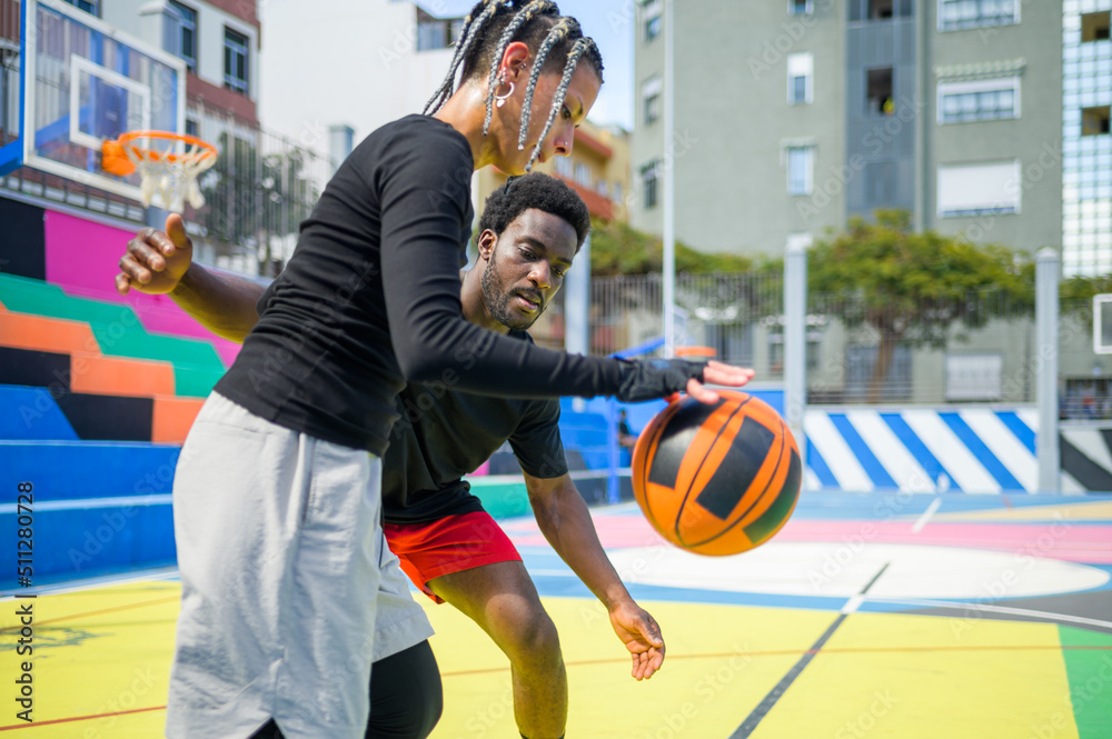 Black man with woman playing basketball