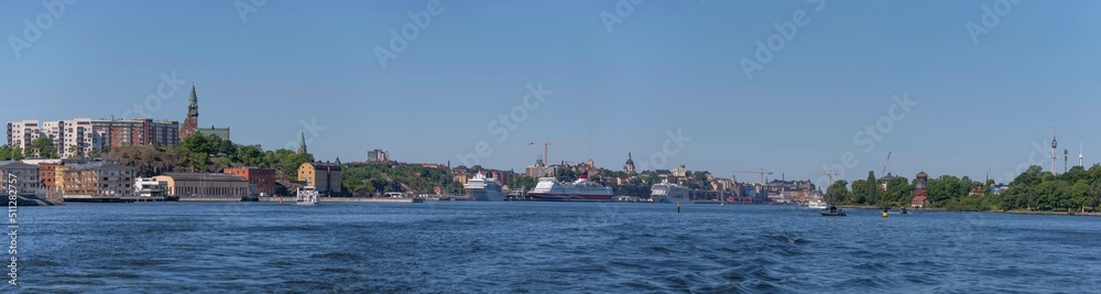 Panorama view over the bay Saltsjön with apartment houses in the district Nacka commuting boats and cruise ships a sunny summer day in Stockholm  