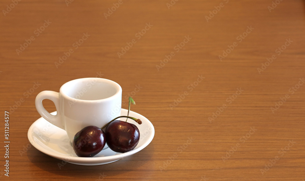 Obraz premium A cup of coffee with two red cherries, on a wooden table