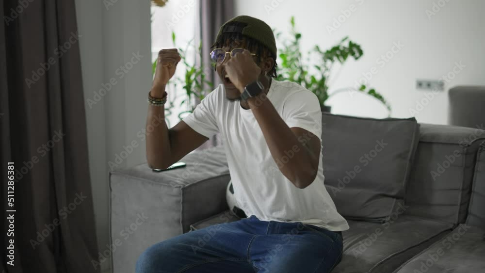 Worried black man watching game on TV, celebrating goal Worried black man watching game on TV, celebrating goal