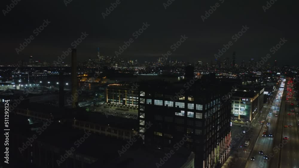 Night flight above city. Factory buildings and busy multilane trunk road in urban neighbourhood. New York City, USA