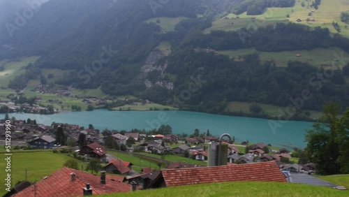 Stunning turquoise Lake Lungerersee with clear water, Landscape view of the roofs of traditional swiss houses, green meadows, lawn. Incredibly bewitching and calm place.