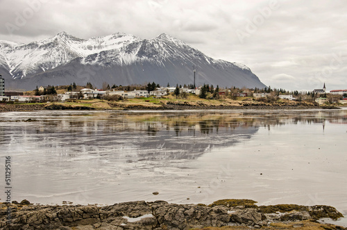 Borgarnes, Iceland, May 7, 2022: the town and the mountains behind it reflecting on the mudflats in the fjord at low tide photo