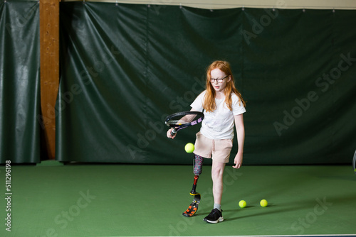 Girl with artificial leg playing tennis photo