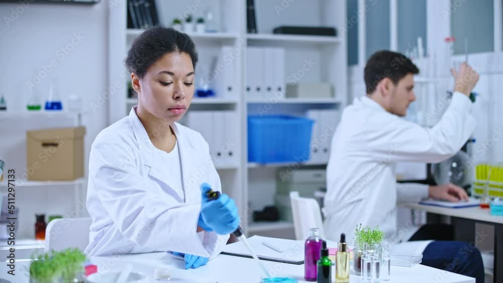 Cosmetology lab scientists studying organic plant extracts, writing test report Cosmetology lab scientists studying organic plant extracts, writing test report